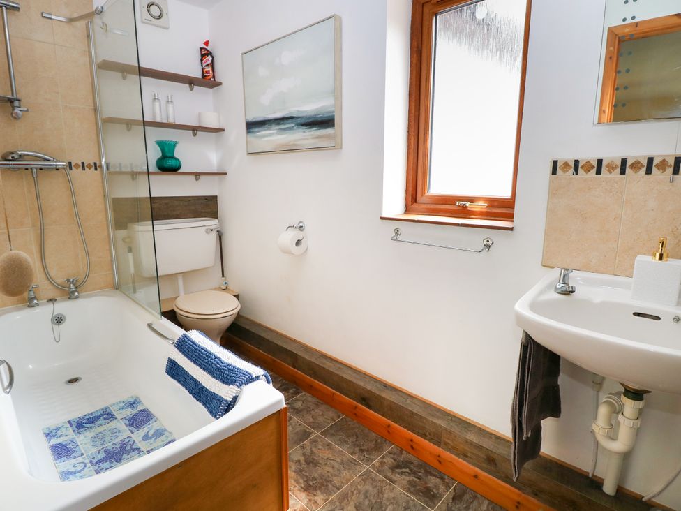A bathroom with a bathtub, toilet, and sink at Dragonfly Lodge in Whinburgh near Dereham