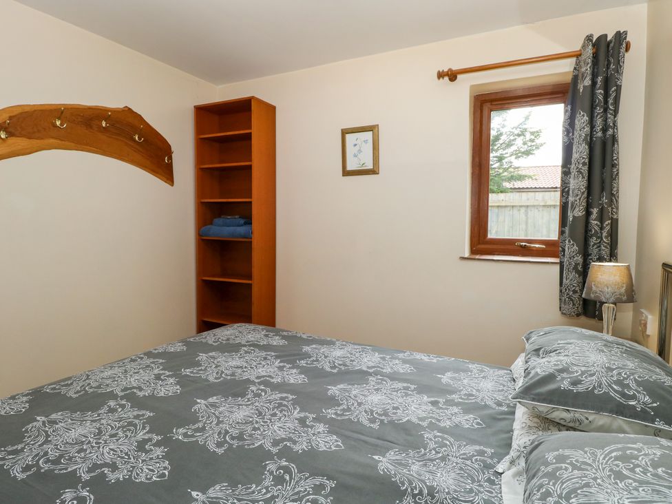 A bedroom with a bed and bookshelf at Dragonfly Lodge in Whinburgh near Dereham