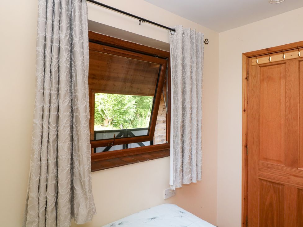 A bedroom with a window and curtains at Dragonfly Lodge Whinburgh near Dereham