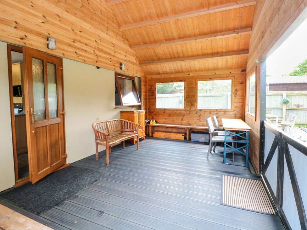 A conservatory with seating and table at Dragonfly Lodge Whinburgh near Dereham