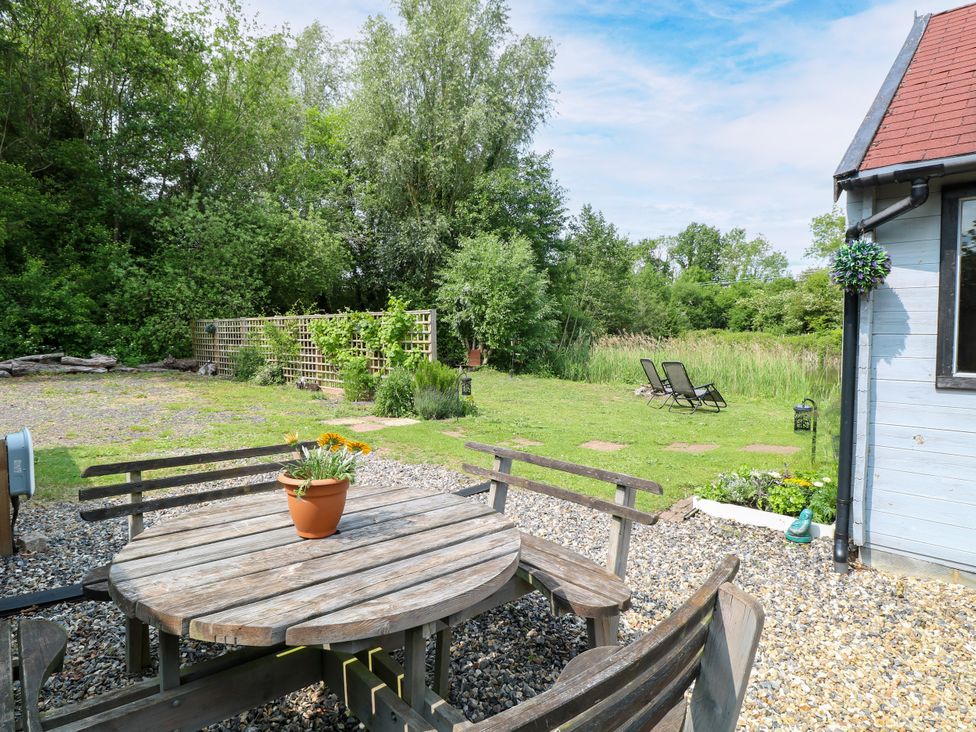 A garden with a wooden table and flower pot at Dragonfly Lodge Whinburgh near Dereham