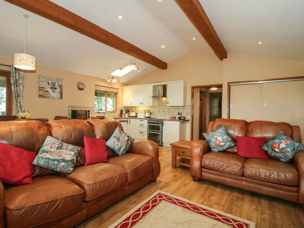 A living room with leather sofas and a kitchen area at Valley View Lodge in Welshpool
