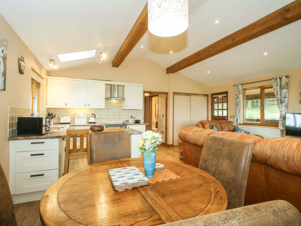 A dining area with a kitchen and sofa at Valley View Lodge in Welshpool
