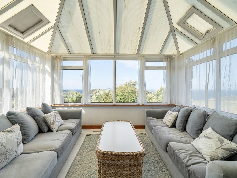 A conservatory with sofas and a table at Tregiffian Vean Sennen Cove