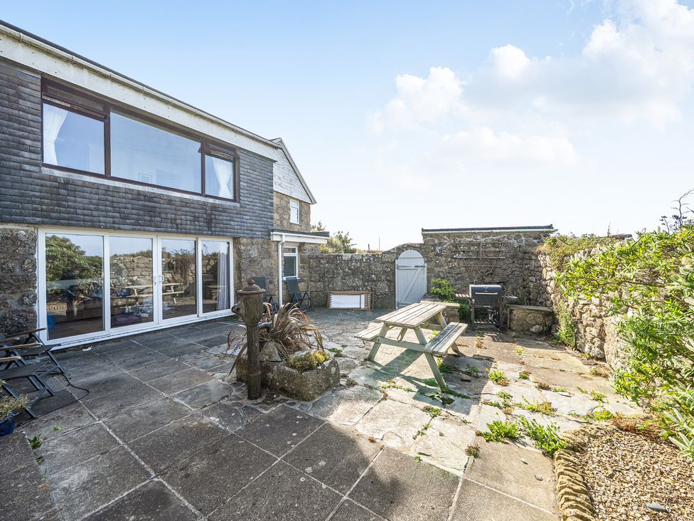 A garden with a patio and seating area at Tregiffian Vean Sennen Cove