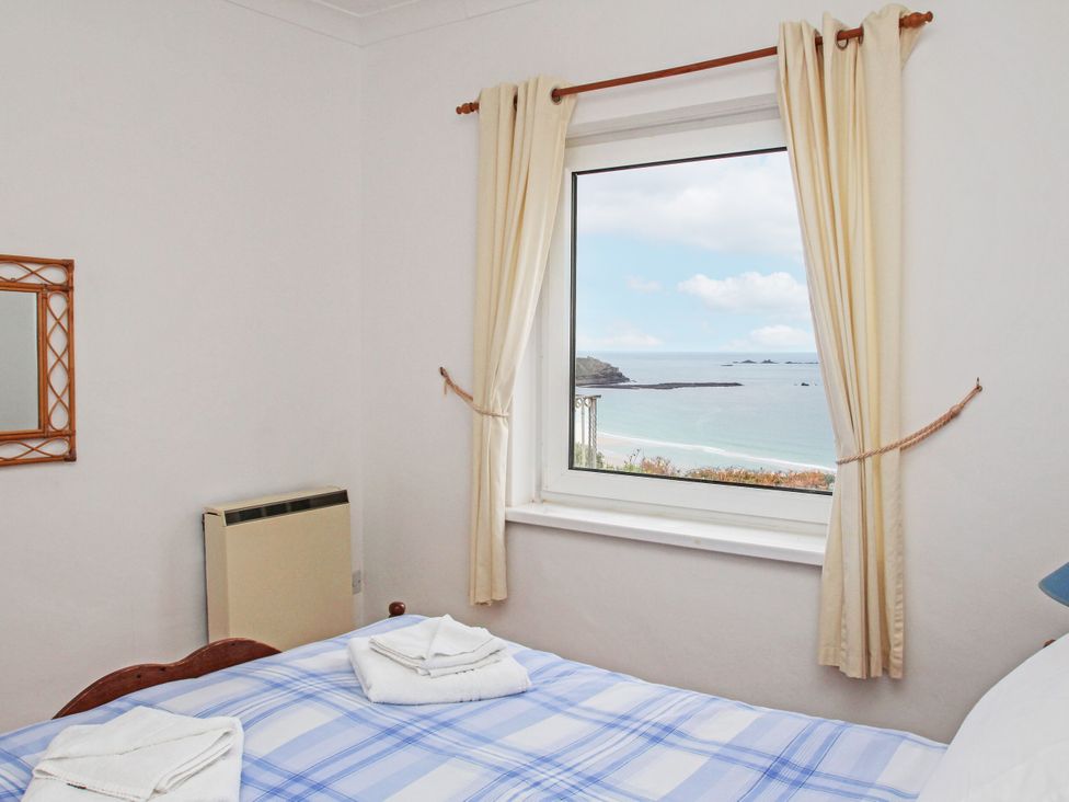 A bedroom with a window overlooking the sea at The Lookout in Sennen