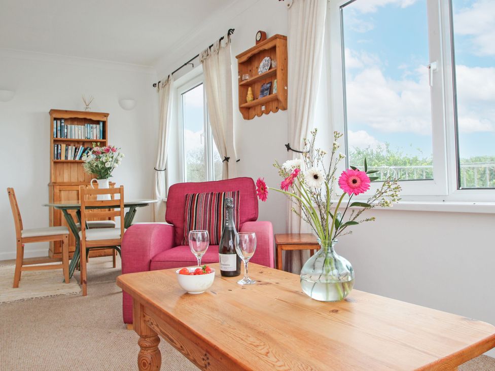 A living room with a pink sofa, coffee table and bookshelf at The Lookout in Sennen