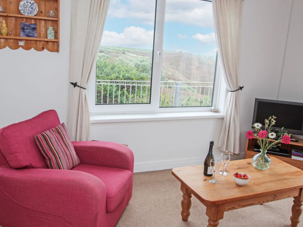 A living room with an armchair and a coffee table at The Lookout in Sennen