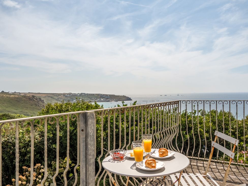 A table with croissants and orange juice on a balcony overlooking the sea at The Lookout in Sennen
