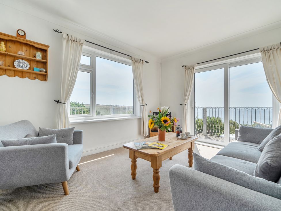 A living room with a sofa, coffee table and flowers at The Lookout in Sennen