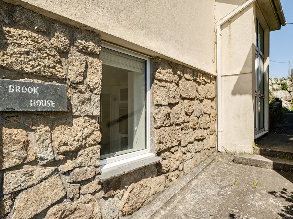 The exterior wall of Brook House with a stone finish and window at Brook House in Sennen Cove near St Just