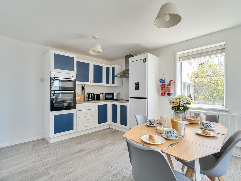 A kitchen with appliances and dining table at Brook House Sennen Cove near St Just