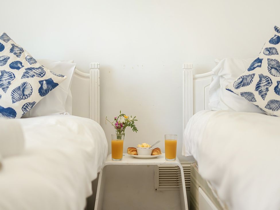 A bedroom with two beds and a table between them at Brook House Sennen Cove near St Just