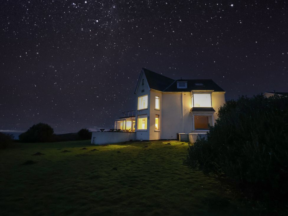 A house with illuminated windows and stars in the sky at Carn Eve Sennen Cove near St Just