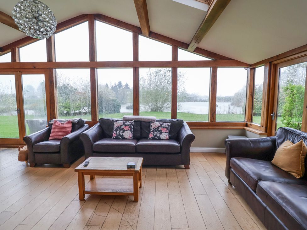 A conservatory with sofas and a coffee table at Manor Wood in Farndon