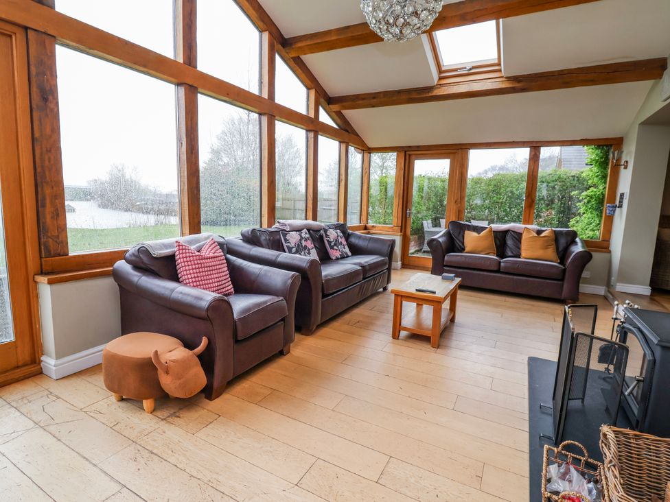 A conservatory with sofas and a coffee table at Manor Wood in Farndon