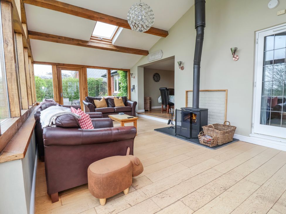 A living room with a stove and sofas at Manor Wood in Farndon