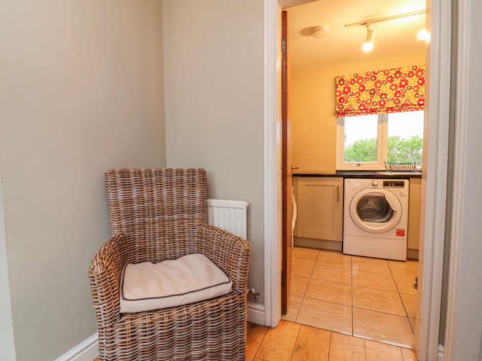 A laundry room with a washing machine and a chair at Manor Wood in Farndon