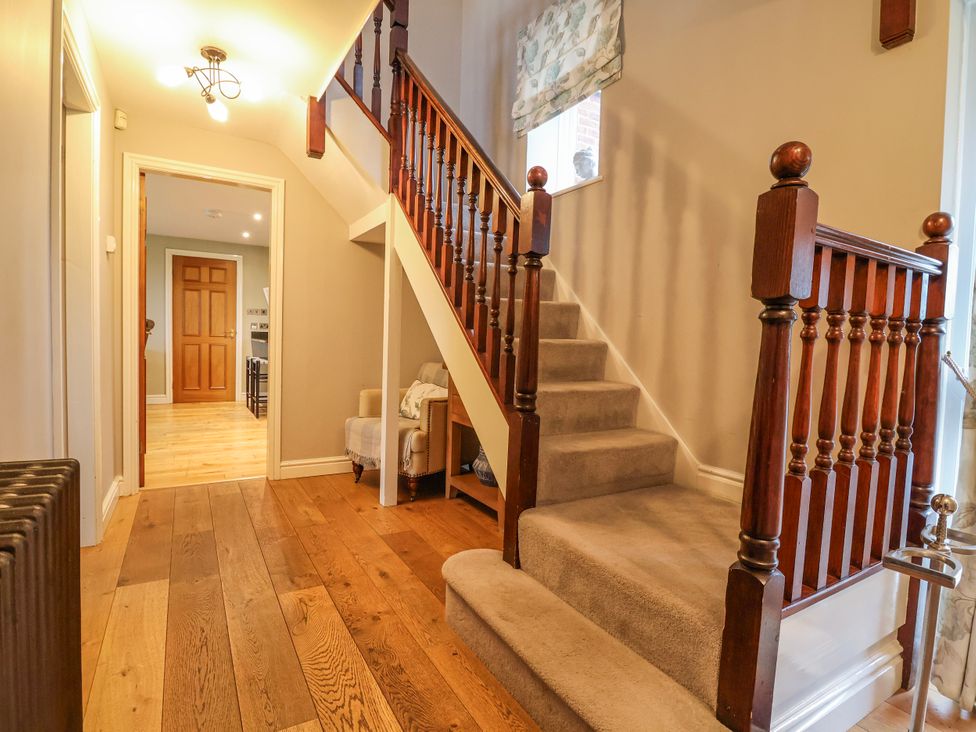 A hallway with a staircase and a door at Manor Wood in Farndon