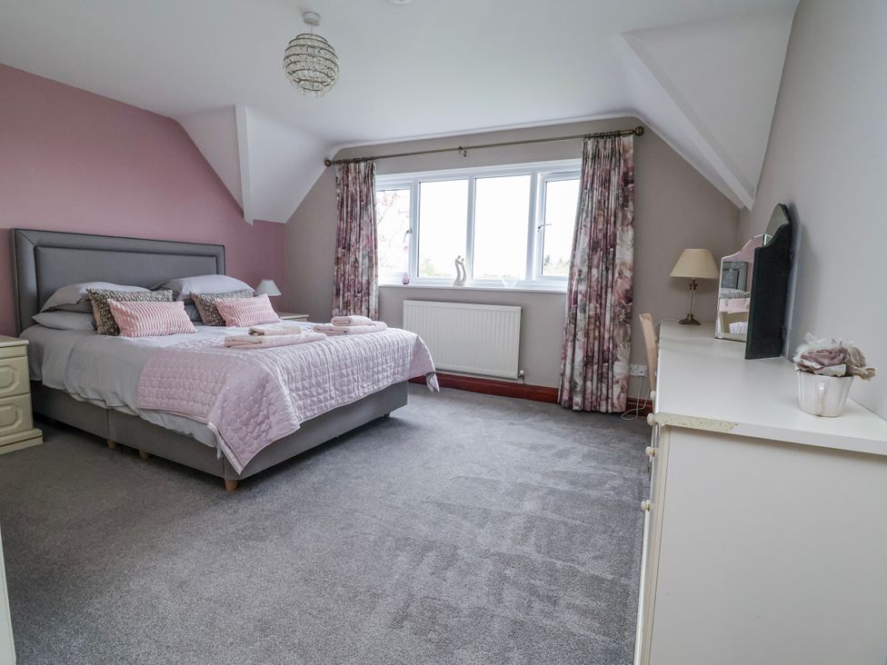 A bedroom with a bed, window, and dressing table at Manor Wood in Farndon