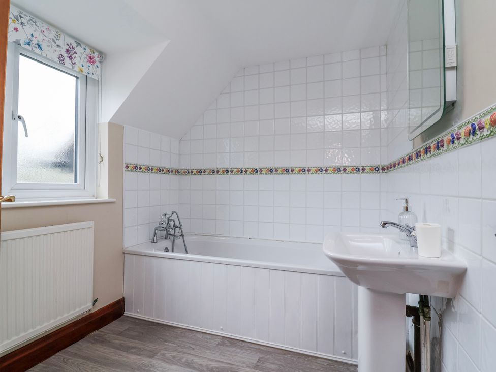 A bathroom with a bathtub and sink at Manor Wood, Farndon