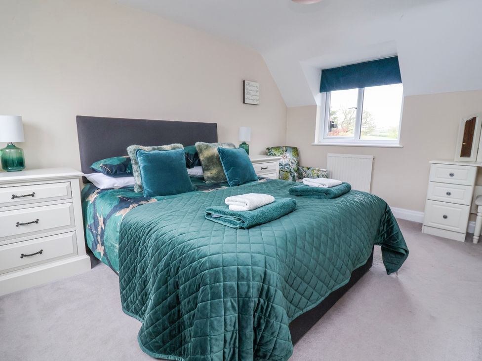 A bedroom with a bed, bedside table, and dresser at Manor Wood in Farndon