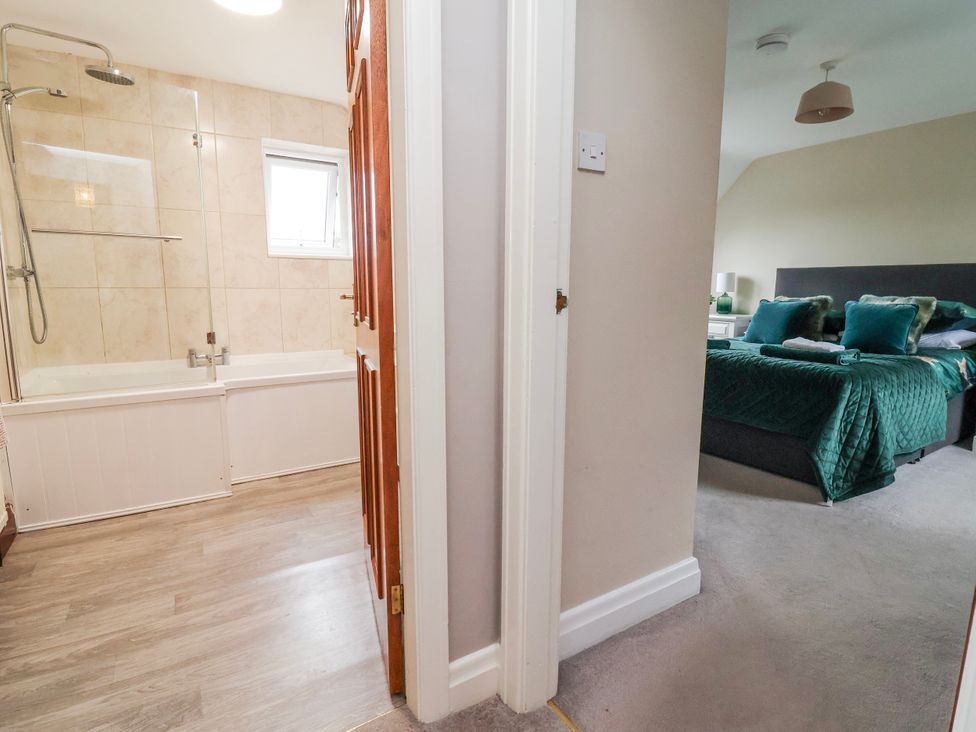 A bathroom with a bathtub and a doorway leading to a bedroom at Manor Wood in Farndon