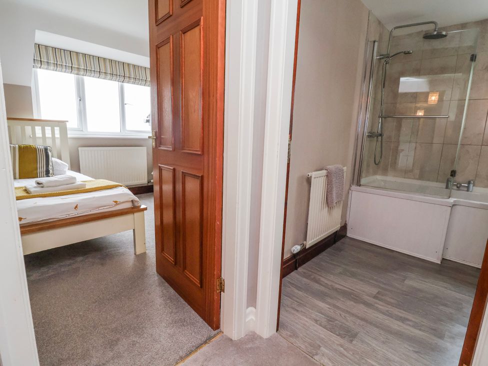 A bedroom with a bed and an adjoining bathroom at Manor Wood in Farndon