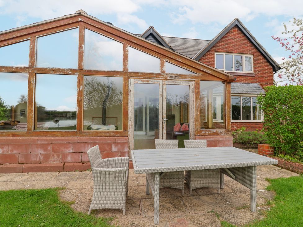 A garden with a conservatory and outdoor furniture at Manor Wood Farndon