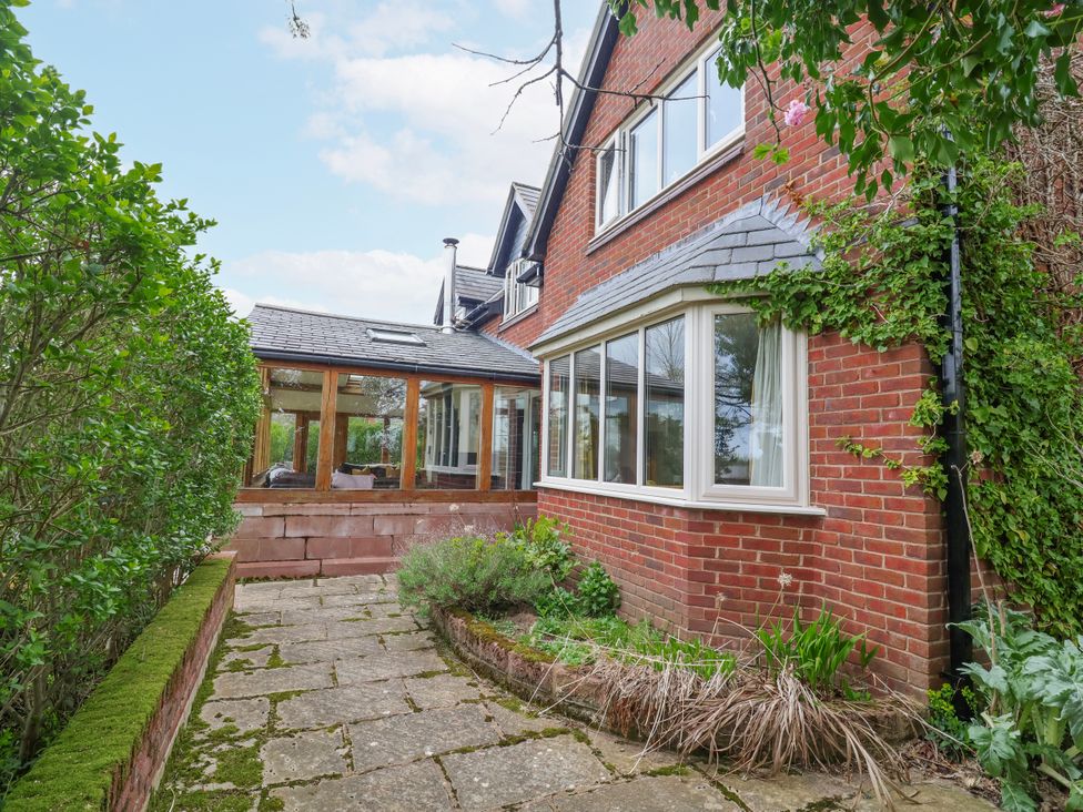 A garden with a brick wall and a conservatory at Manor Wood in Farndon