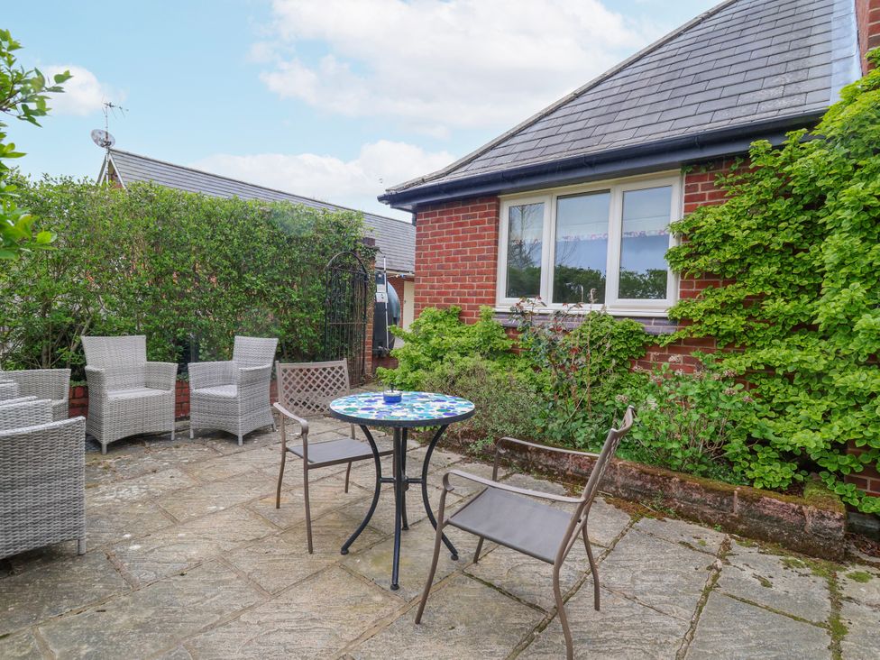 An outdoor patio with chairs and a table at Manor Wood in Farndon