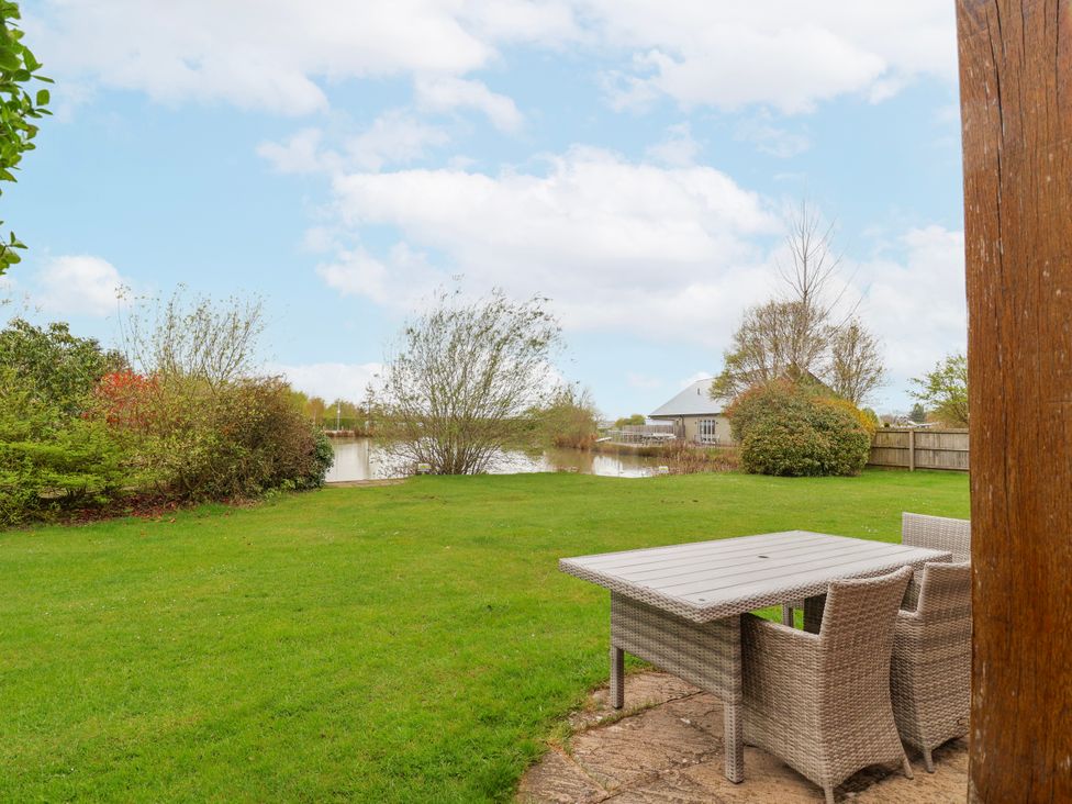 A garden with a table and chairs overlooking a water at Manor Wood in Farndon