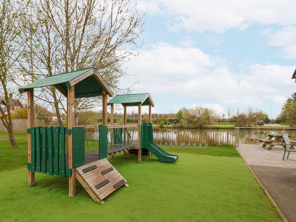 A playground structure with slide and bridge by a pond at Manor Wood in Farndon