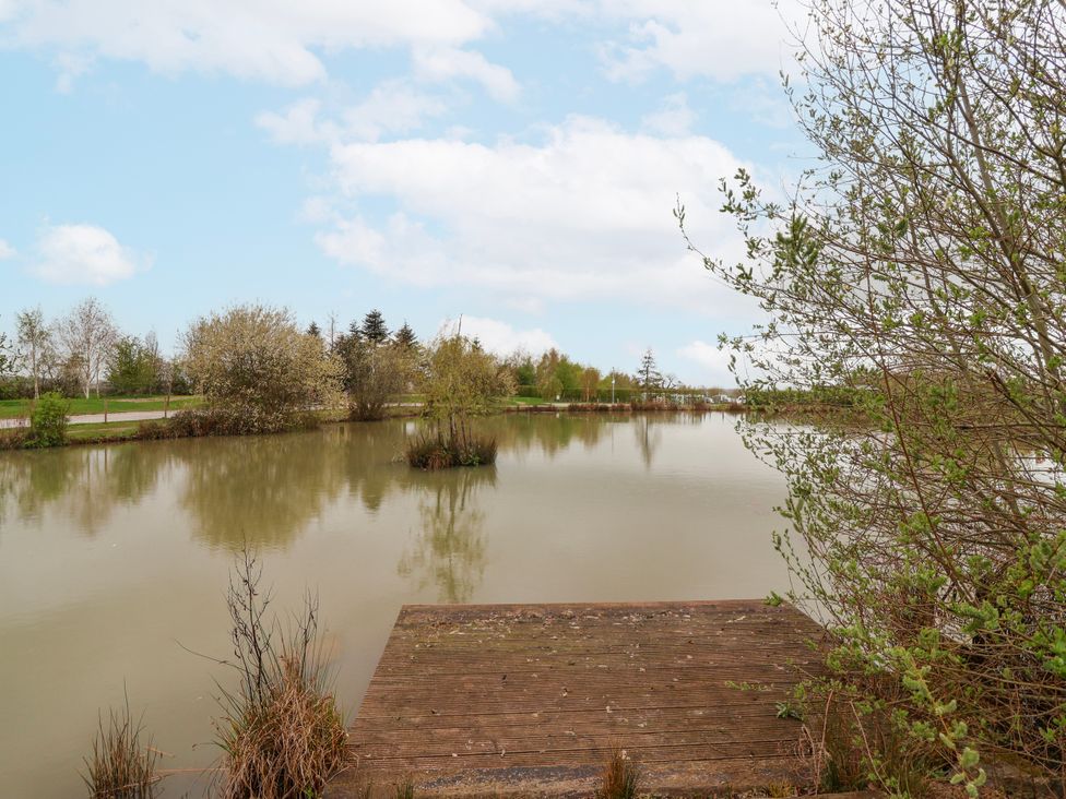 A water view with a dock and trees at Manor Wood Farndon