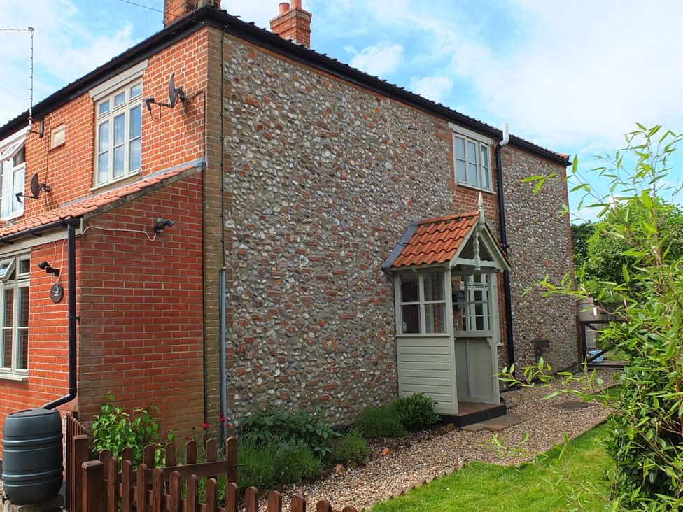 An outdoor view of a house with a porch and garden at COO - Beaconsfield Cottage in Melton Constable