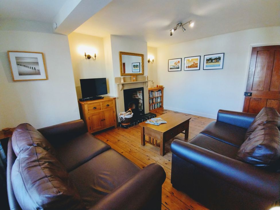 A living room with two sofas, a fireplace, and a television at COO - Beaconsfield Cottage in Melton Constable