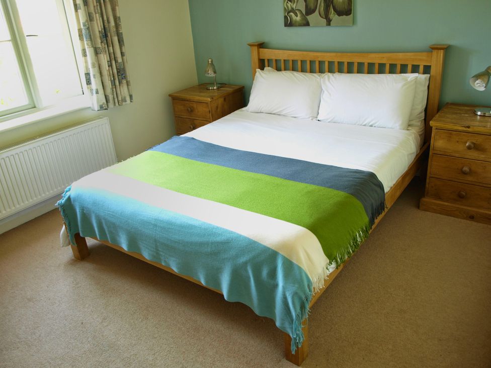 A bedroom with a bed and bedside table at COO - Beaconsfield Cottage, Melton Constable