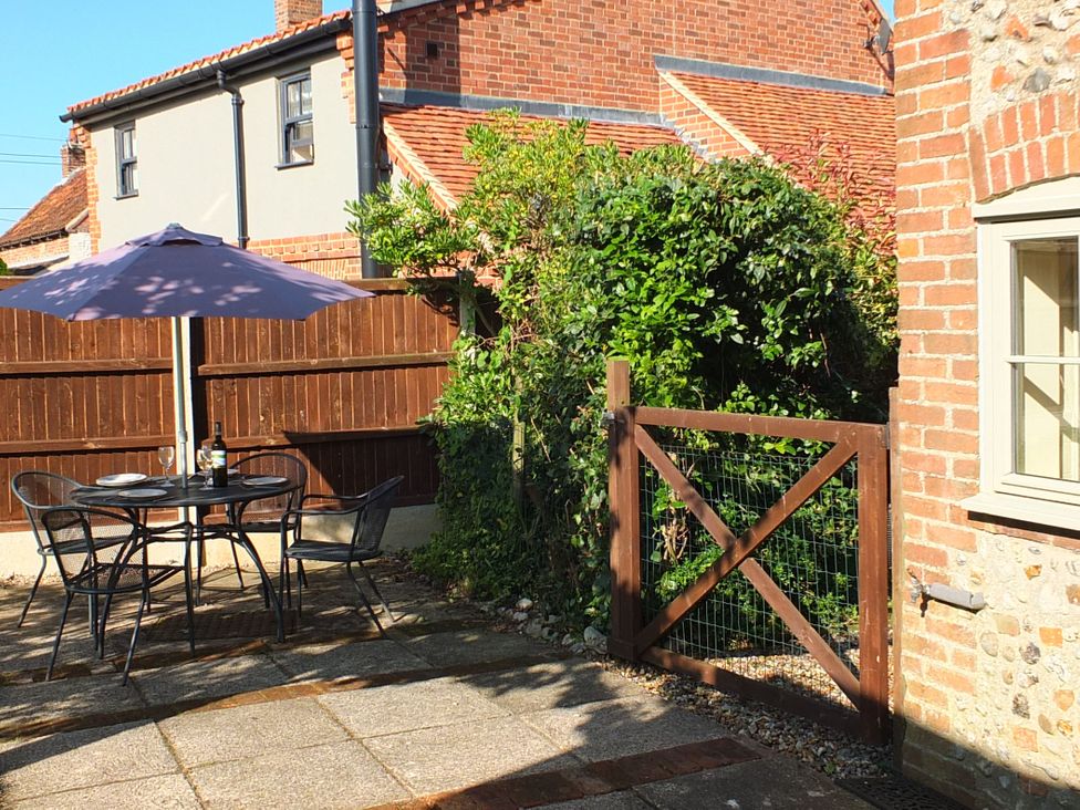 A garden with a table and chairs under an umbrella at COO - Beaconsfield Cottage Melton Constable