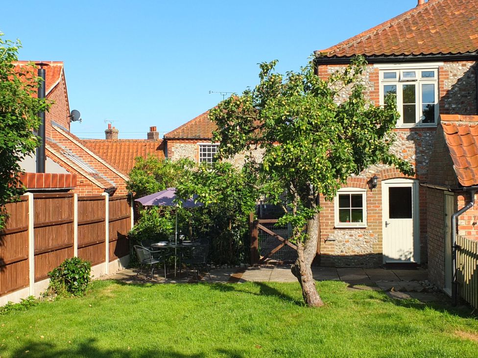 A garden with a table and chairs under an umbrella at COO - Beaconsfield Cottage Melton Constable