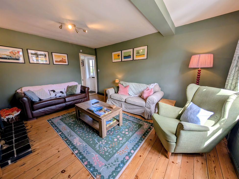 A living room with a sofa and armchair at Beaconsfield Cottage in Briston