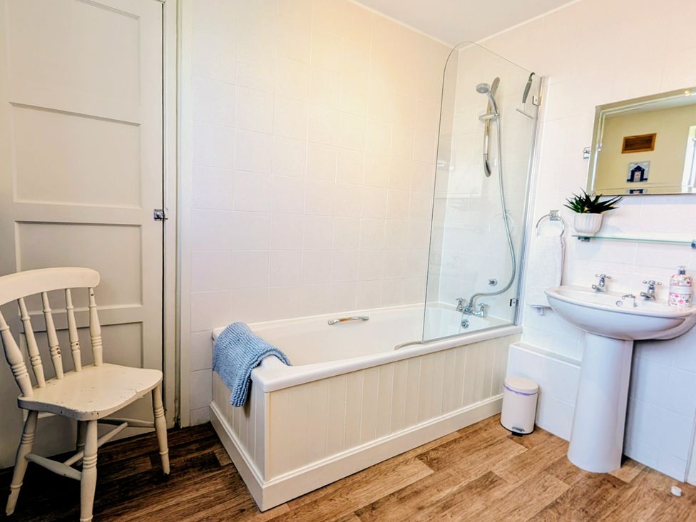 A bathroom with a bathtub, sink, and shower at Beaconsfield Cottage in Briston