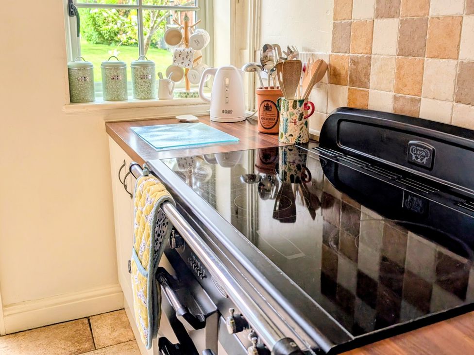 A kitchen with a stove and kettle at Beaconsfield Cottage in Briston