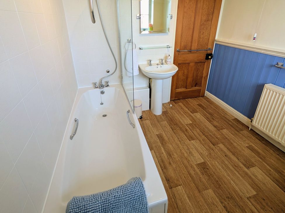 A bathroom with a bathtub and sink at Beaconsfield Cottage in Briston