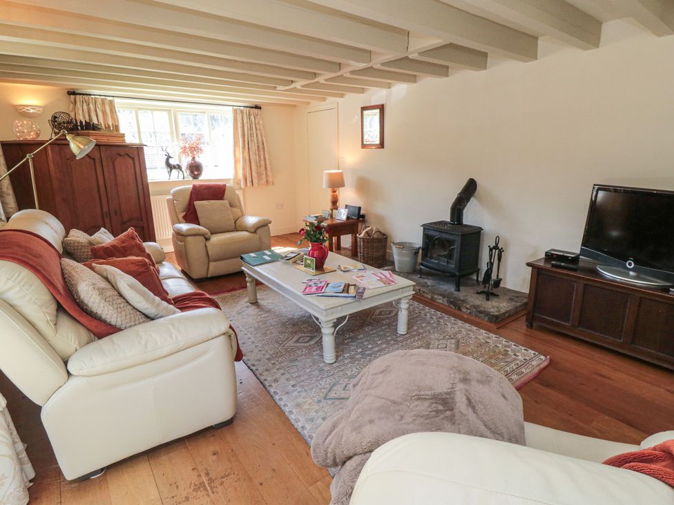 A living room with a sofa, armchair, coffee table and television at Quoits Cottage in Beck Hole near Goathland