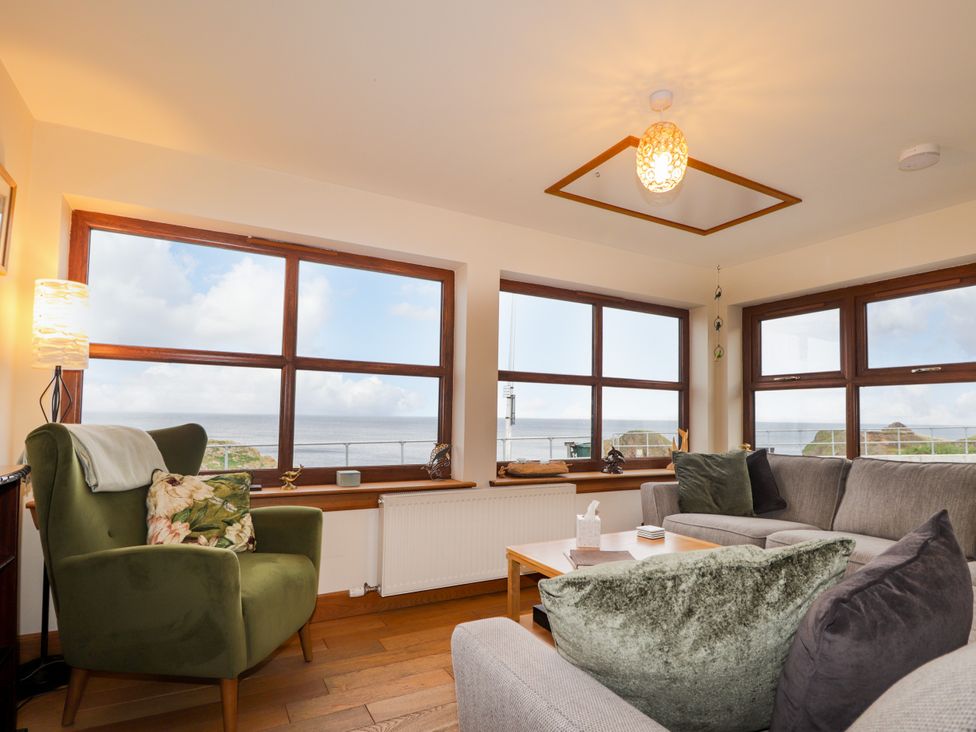 A living room with a sofa, armchair, and large windows at Seascape in Portknockie