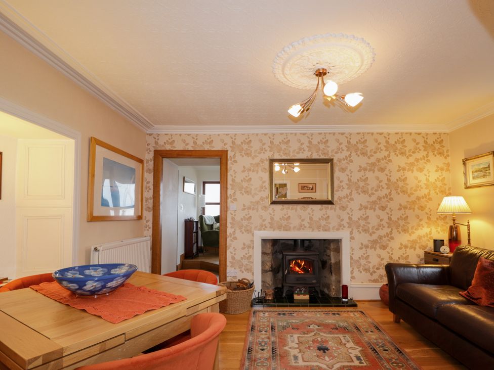 A living room with a fireplace and a dining table at Seascape in Portknockie