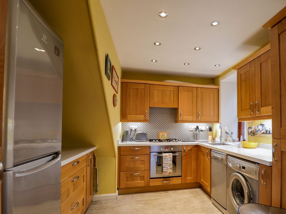 A kitchen with wooden cabinets and appliances at Seascape in Portknockie