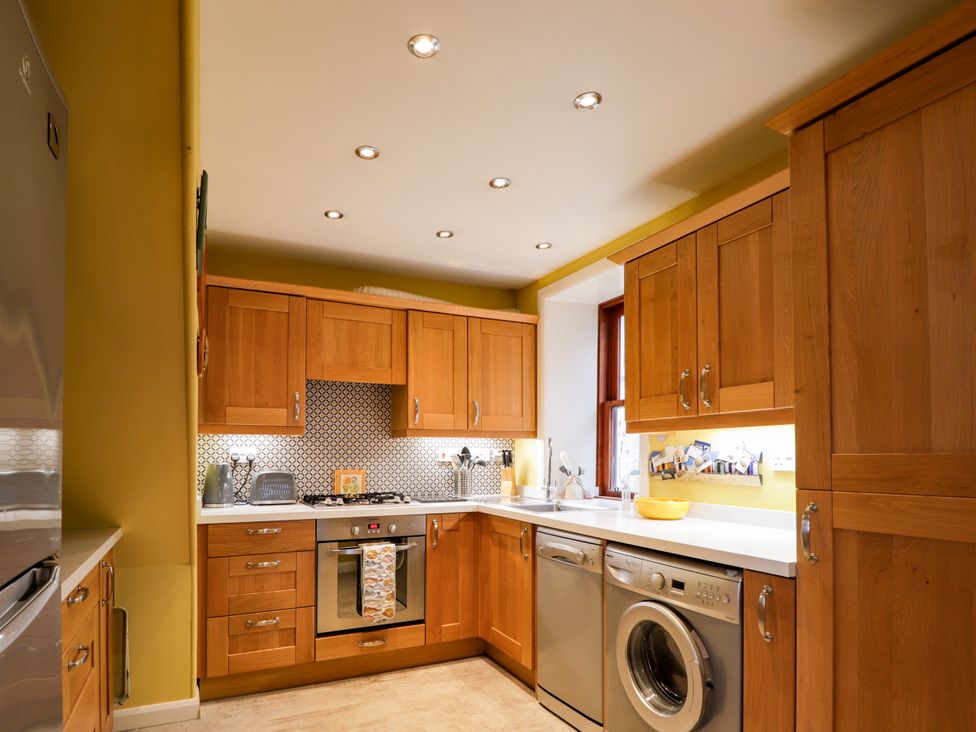 A kitchen with wooden cabinets and appliances at Seascape in Portknockie