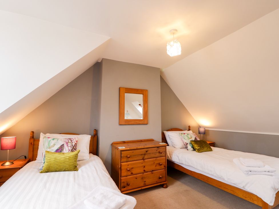 A bedroom with two beds and a mirror at Seascape in Portknockie