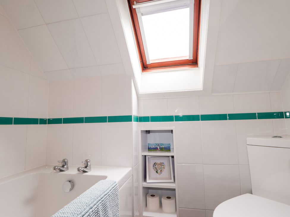 A bathroom with a bathtub, toilet, and shelf at Seascape in Portknockie